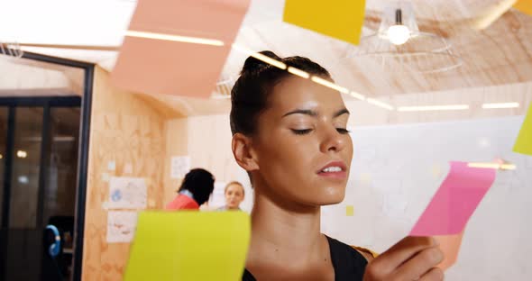 Business executive sticking sticky note on glass