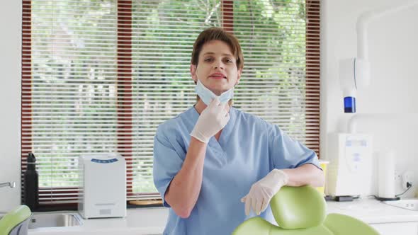 Portrait of smiling caucasian female dental nurse with face mask at modern dental clinic
