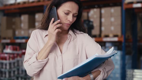 Caucasian elegance woman talking by mobile phone in warehouse. Shot with RED helium camera in 8K.