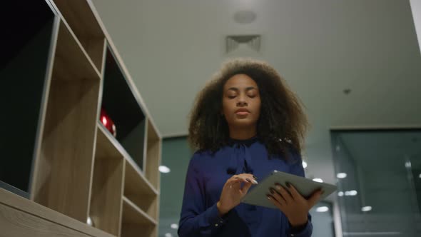 African American Business Woman Going in Office Hallway Browsing Tablet Indoors