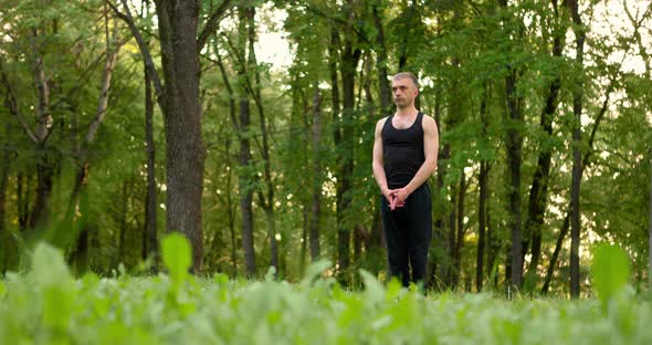 Men Practicing Yoga and Meditating in Park at Sunny Summer Day