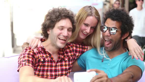 Three young adults having fun taking spontaneous selfies