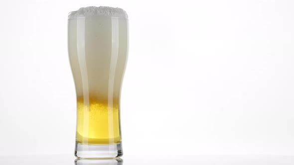 Pouring beer in glass, on white background. 4K UHD video