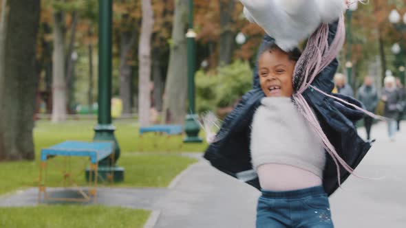 Little Cute Girl Playing in City Park African Child Whirling Around Holding Teddy Bear Afro American