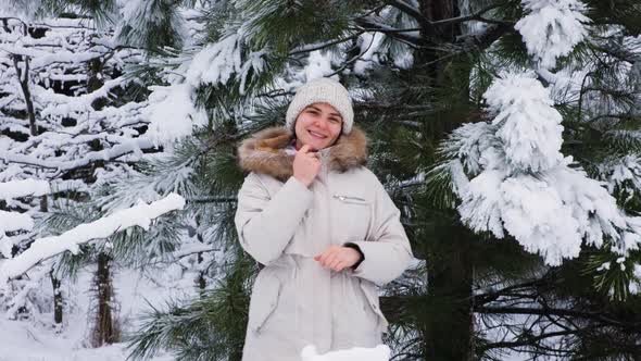 A Beautiful Woman Has Fun in a Winter Pine Forest Looking Into the Camera