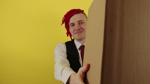 Young Man in White Shirt Vest and Tie with Cardboard Box on Yellow Background in Studio