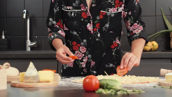 Making italian pizza at home. Cooking process, adding tomatoes to pizza base