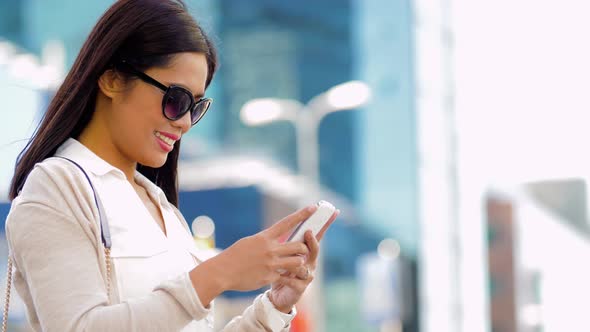 Asian Woman in Sunglasses Using Smartphone in City