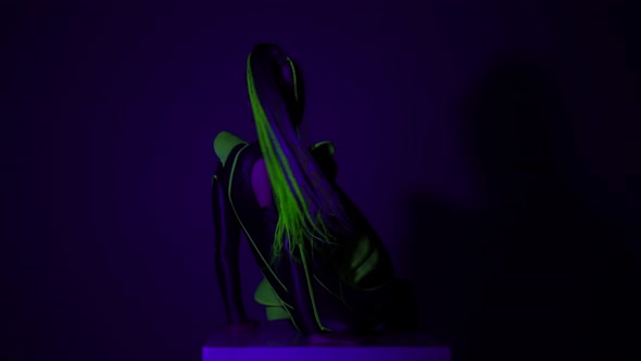 Young Slim Woman Sitting on Cube in Strobe Lights Looking at Camera Bending and Leaving