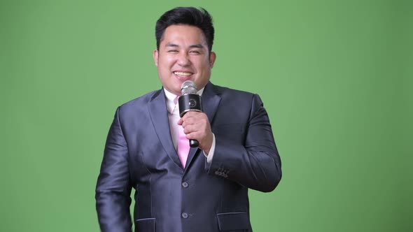 Young Handsome Overweight Asian Businessman Against Green Background