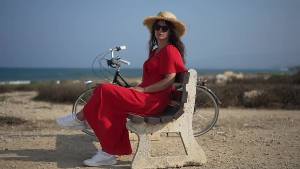 Side View Young Thoughtful Woman with Bike Sitting on Bench Looking Around in Slow Motion