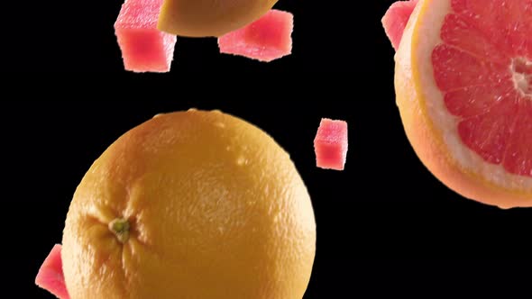 Grapefruit with Slices Falling on Black Background