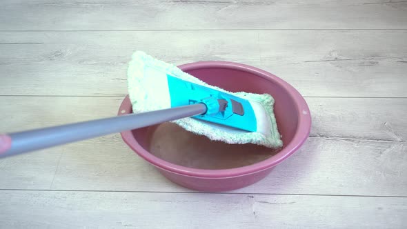 Putting the Blue Mop in a Bowl of Water to Start Cleaning the Fray Floor Later