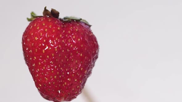 A Drop of Water Drips on a Large Ripe Strawberry