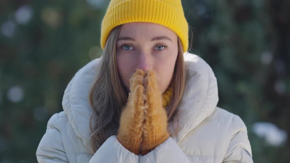 Portrait of Slim Beautiful Young Caucasian Woman in Yellow Hat and Mittens Rubbing Hands Looking at