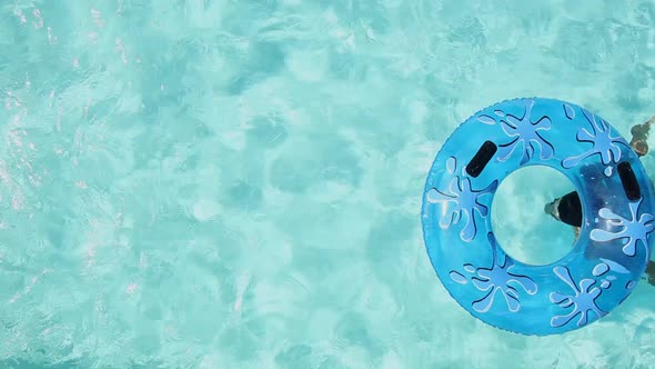 Man Swimming in Pool with Inflatable Ring