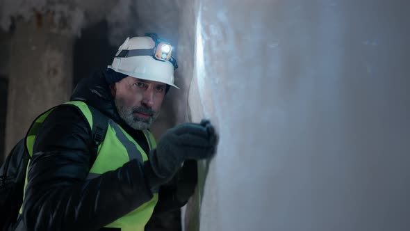 Portrait of Concentrated Man Examining Snow Wall in Ice Cave