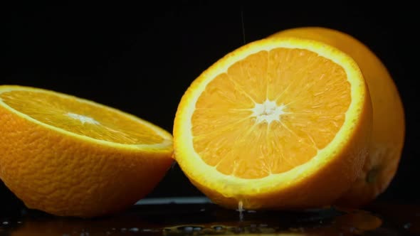 Water Pours on a Juicy Bright Orange in Slow Mo on a Black Background