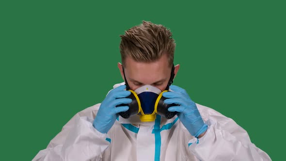 Portrait of a Male Doctor in a White Protective Suit and Surgical Gloves Looking at the Camera Puts