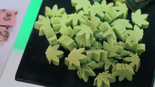 Green Cannabis CBD CBG Weed Cookies Shaped Like Marijuana Leaves Laying Down on a Black Plate