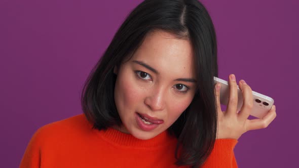 Serious woman in red sweater listening a voice message on the phone