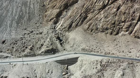 aerial drone tracking a local white car on the dirt highway road in the rugged mountains of Skardu P