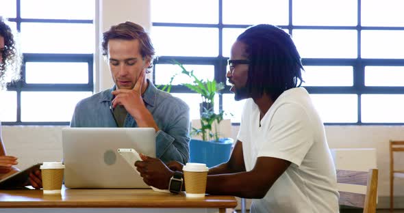 Colleagues discussing with each other over laptop