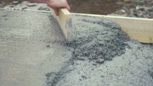 Tapping flattening fresh cement with wooden board