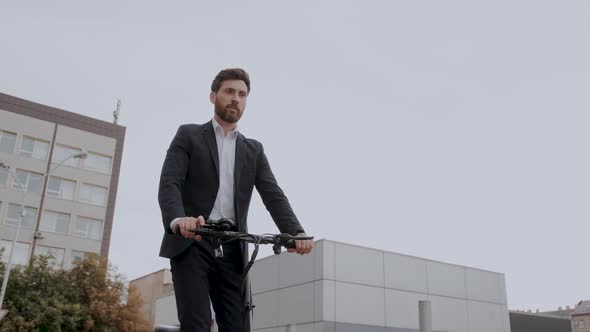 Young Modern Business Man in a Suit Riding an Electric Scooter