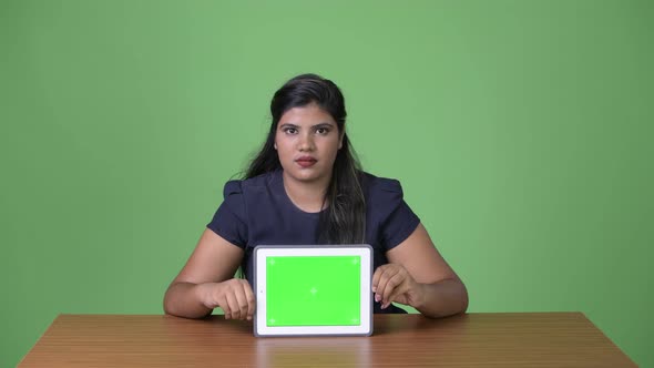 Young Overweight Beautiful Indian Businesswoman Against Green Background