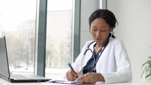 Young African American Woman Doctor Having Chat or Consultation on Laptop