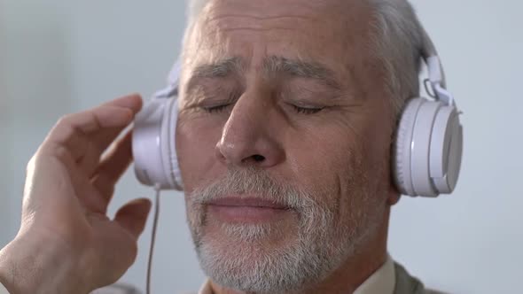 Pensive Old Man in Headphones Listening to Music, Remembering Youth, Nostalgia