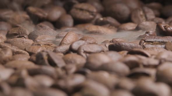 Close up slow motion shot of roasting coffee beans as smoke starts to appear bringing out the beauti