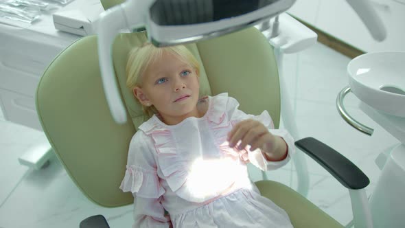 Girl Sits in Dental Chair, Turn Off and on the Lamp