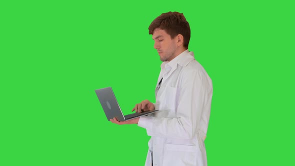 Male Doctor in White Coat Having Video Conference on His Laptop on a Green Screen, Chroma Key.