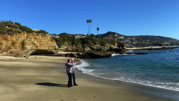 Senior couple at the beach. Walking along the shoreline towards camera. 4k, 24p, slow motion.