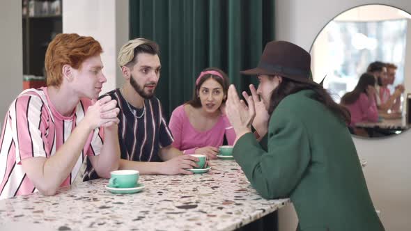 Group of Absorbed Friends Listening to Story of Stylish Confident Caucasian Man in Vintage Coffee