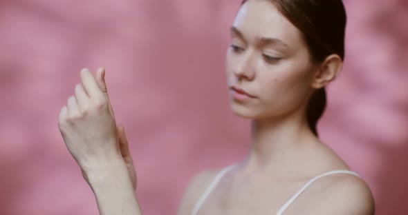 A Young Woman Rubs Moisturizer Into the Skin of Her Hands