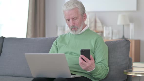 Attractive Old Man Working on Smartphone and Laptop