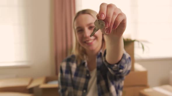 A Happy Woman Holds the Keys to a New Apartment in Her Hand