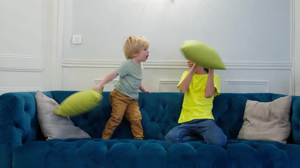 Children Blond Boy and His Brother Fight with Pillows