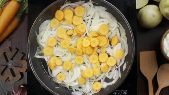 Flat Lay Video: Chef Adds Chopped Carrot To the Onion on the Hot Pan and Stirs It By Wooden Kitchen