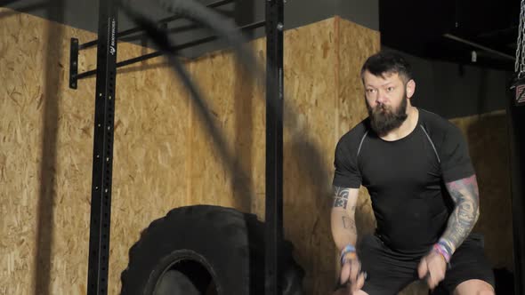 Athletic Male Actively Does Exercises with Battle Ropes on Cross Fitness Workout