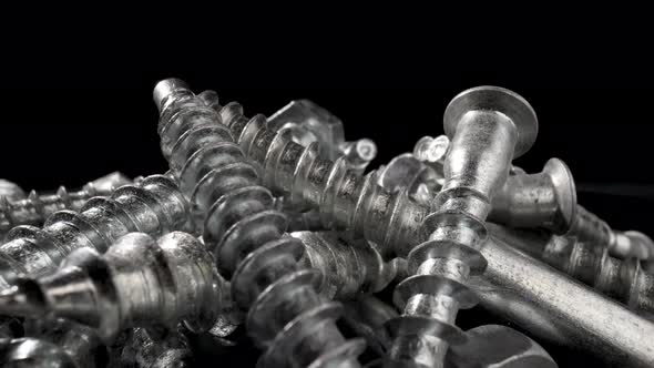 Pile of Steel Chrome Screws Rotating on Isolated Black Background