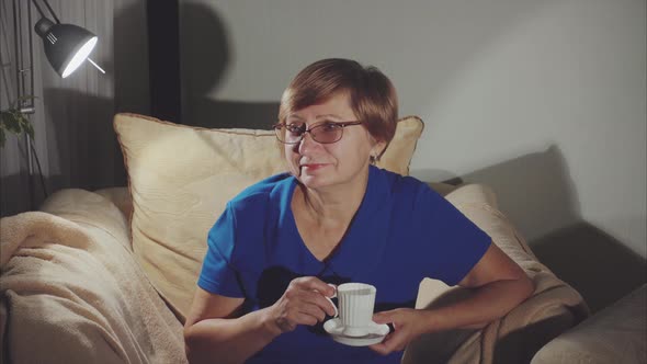 Older Woman Drinking Tea Sitting on the Chair