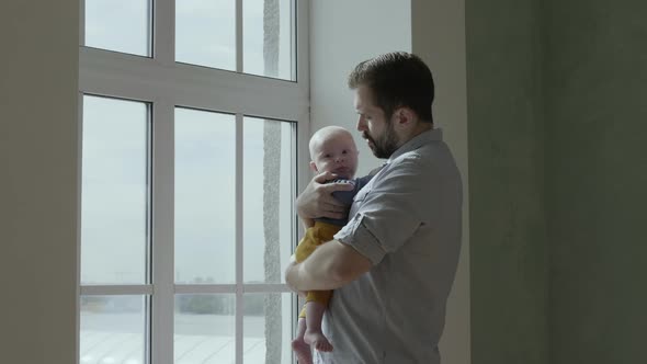 Dad holding baby near a window