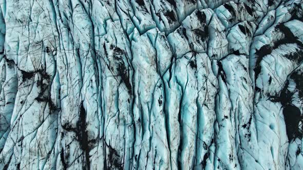 Drone Over Cracked Black And Blue Surface Of Glacier