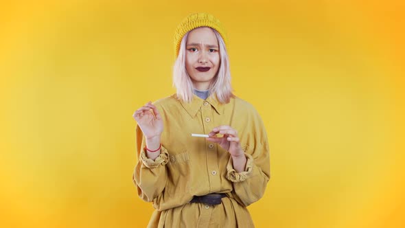 Pretty Unusual Girl Breaking the Last Cigarette Isolated on Yellow 