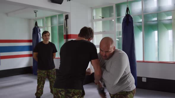 Caucasian man learning self defense from trainer in gym