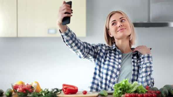 Beautiful Young Housewife Taking Selfie Using Smartphone at Kitchen During Cooking Healthy Food